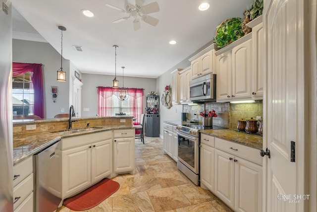 kitchen with sink, light stone countertops, appliances with stainless steel finishes, tasteful backsplash, and decorative light fixtures