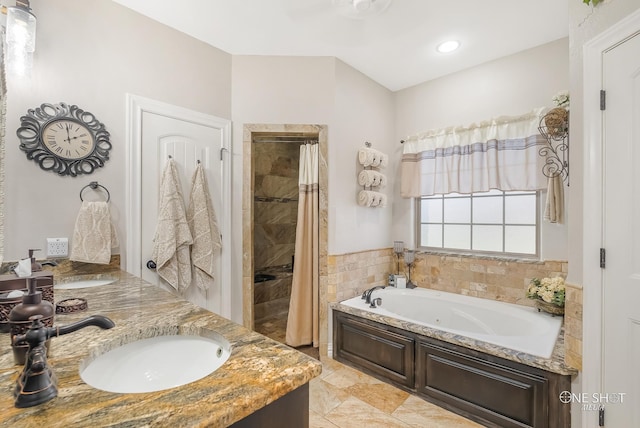 bathroom featuring vanity, independent shower and bath, and tile walls