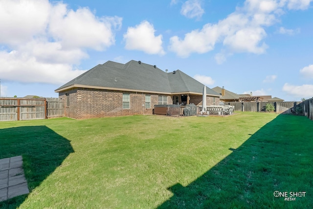 back of house featuring a yard and a hot tub