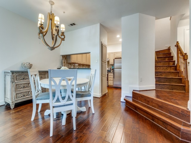 dining space with dark wood-type flooring and a notable chandelier