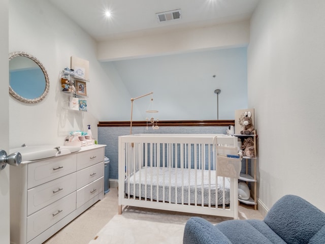 carpeted bedroom featuring a nursery area