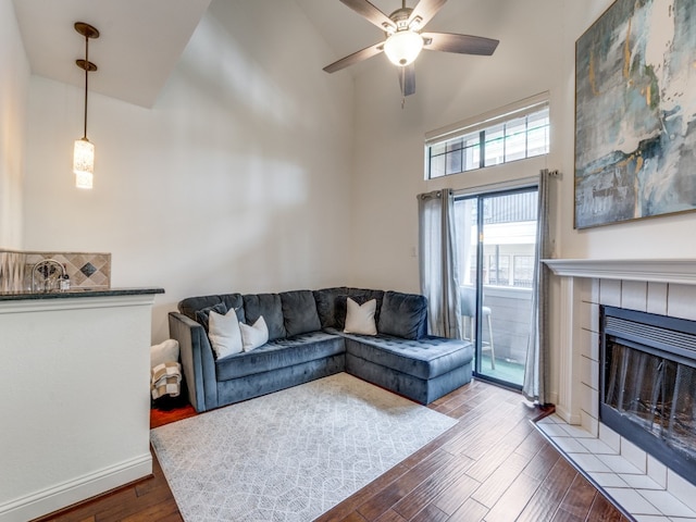 living room with light hardwood / wood-style flooring, a fireplace, ceiling fan, and a high ceiling