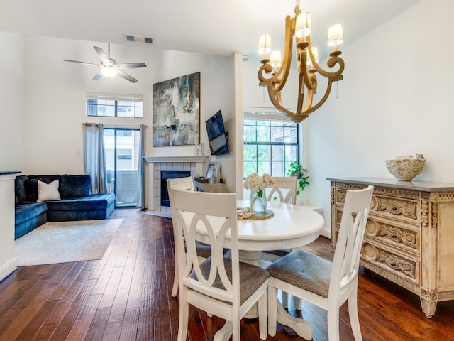 dining space featuring vaulted ceiling, a wealth of natural light, a tiled fireplace, and dark wood-type flooring