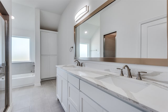 bathroom with vanity, vaulted ceiling, a tub, and tile patterned floors