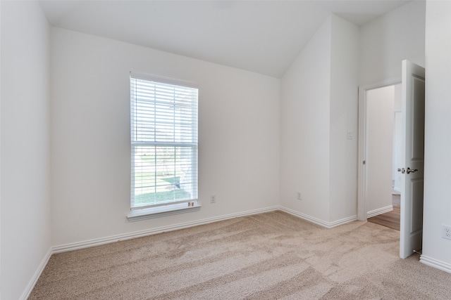 unfurnished room featuring lofted ceiling and light colored carpet