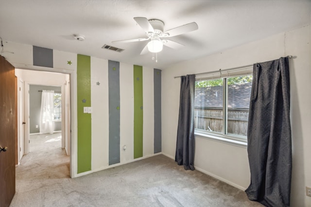 unfurnished room with ceiling fan, plenty of natural light, and light carpet