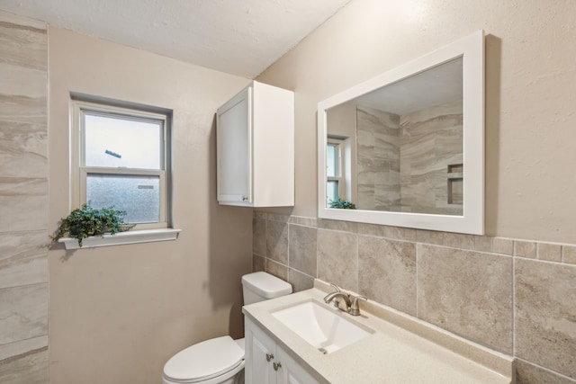 bathroom with vanity, toilet, and tile walls