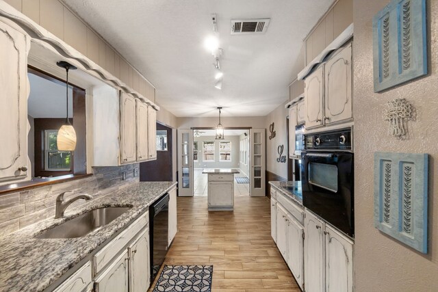 kitchen with light hardwood / wood-style flooring, sink, decorative backsplash, black appliances, and decorative light fixtures