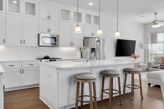 kitchen with stainless steel appliances, white cabinetry, a center island with sink, and sink