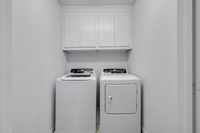 clothes washing area featuring washer and dryer and cabinets