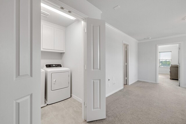 clothes washing area featuring washing machine and dryer, crown molding, light colored carpet, and cabinets