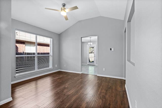 spare room featuring ceiling fan with notable chandelier, dark wood-type flooring, a wealth of natural light, and lofted ceiling