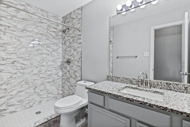 bathroom featuring vanity, toilet, and tiled shower