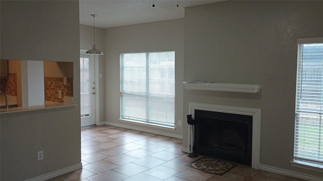 unfurnished living room with a textured ceiling, a wealth of natural light, and light tile patterned flooring