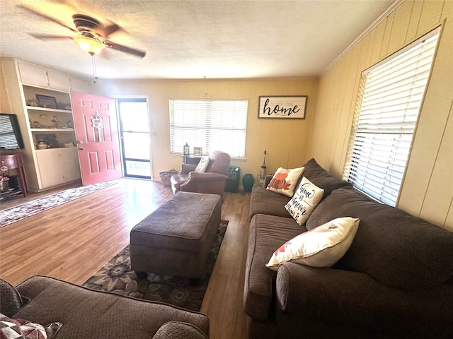 living room with ceiling fan, hardwood / wood-style floors, built in features, and a textured ceiling