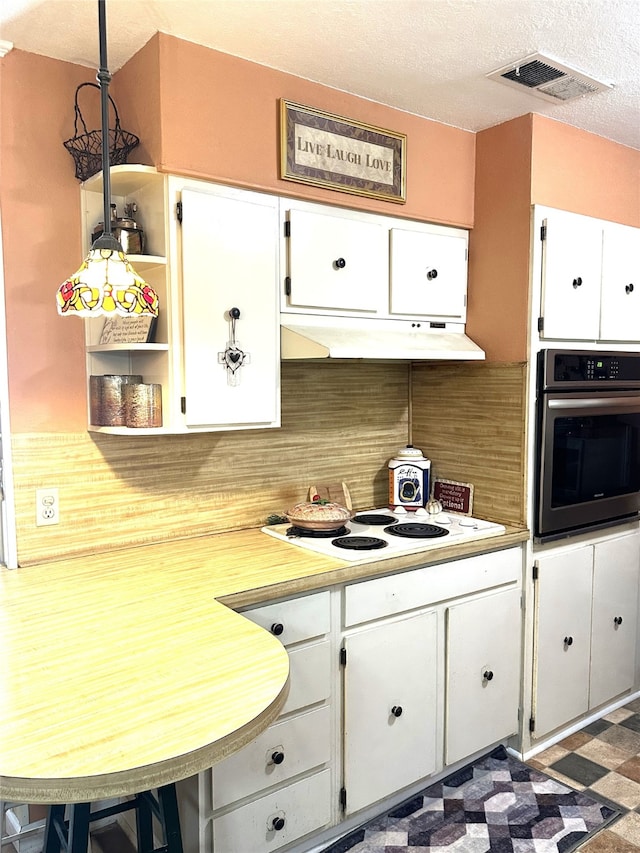 kitchen featuring tasteful backsplash, pendant lighting, white cabinetry, white electric cooktop, and oven