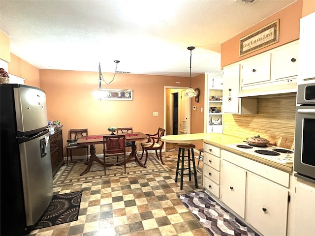 kitchen with decorative light fixtures, white cabinets, stainless steel appliances, and tasteful backsplash