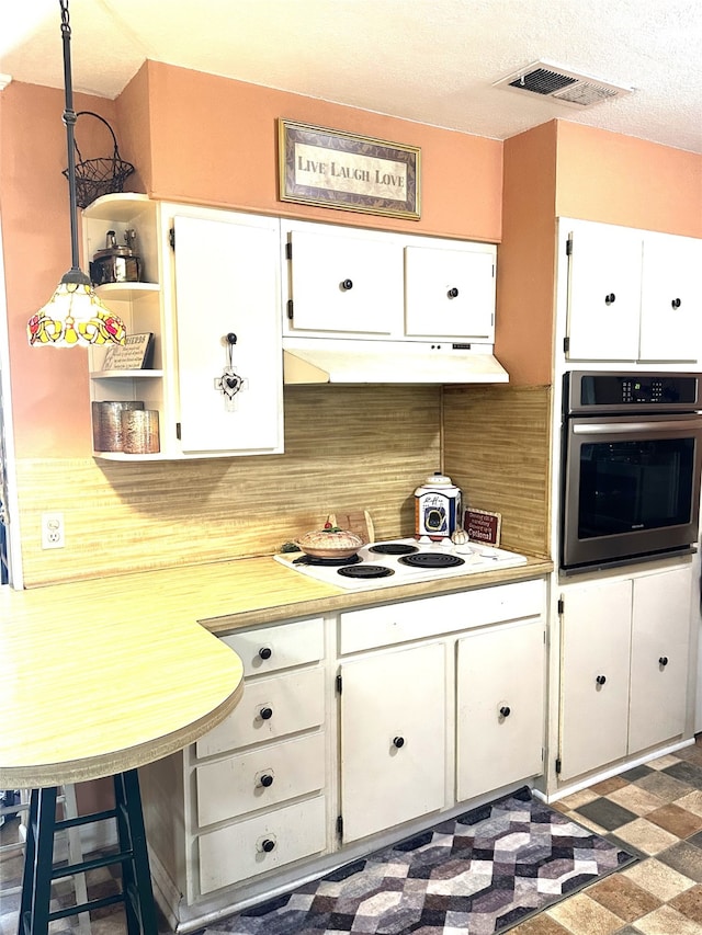 kitchen with white cabinetry, a breakfast bar, hanging light fixtures, stainless steel oven, and white electric cooktop