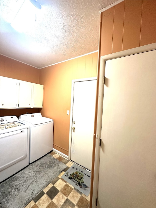 laundry area with washing machine and dryer, cabinets, and a textured ceiling