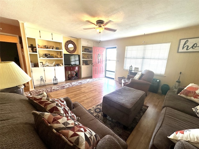 living room with a textured ceiling, hardwood / wood-style flooring, and ceiling fan