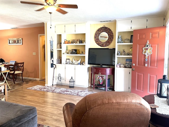 living room with a textured ceiling, light hardwood / wood-style floors, and ceiling fan