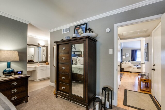 interior space featuring light hardwood / wood-style flooring, ensuite bath, and crown molding