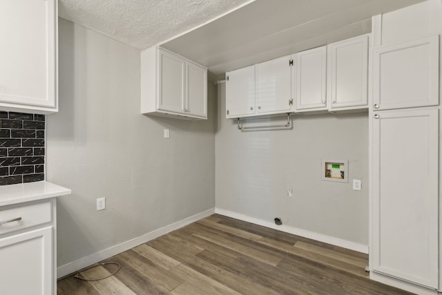 laundry room featuring hardwood / wood-style flooring, cabinets, a textured ceiling, and hookup for a washing machine