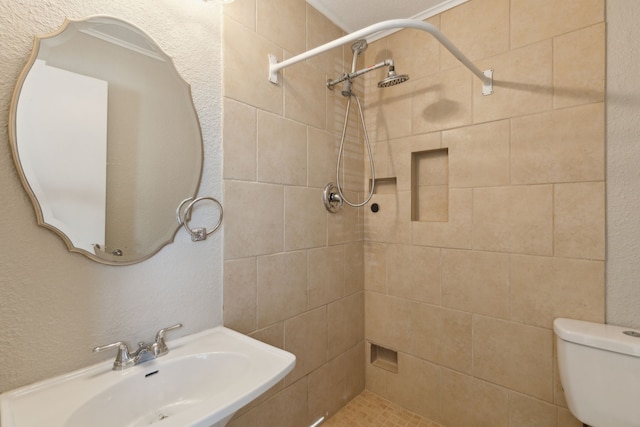 bathroom with tiled shower, toilet, and sink