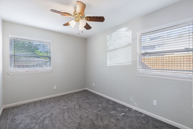 empty room with dark colored carpet and ceiling fan