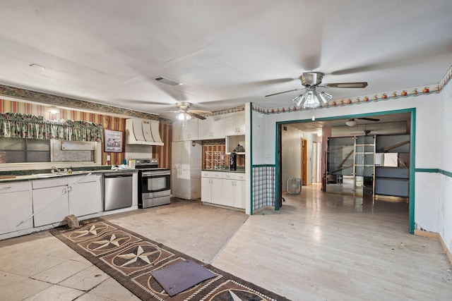 kitchen with appliances with stainless steel finishes, custom range hood, sink, a barn door, and white cabinets