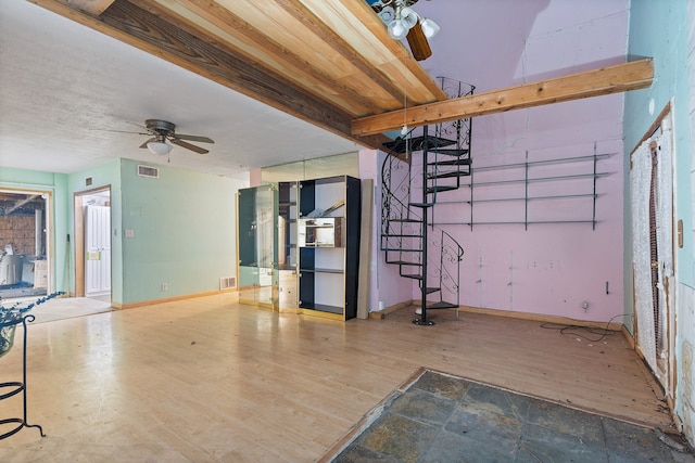 interior space with beam ceiling, hardwood / wood-style flooring, and ceiling fan