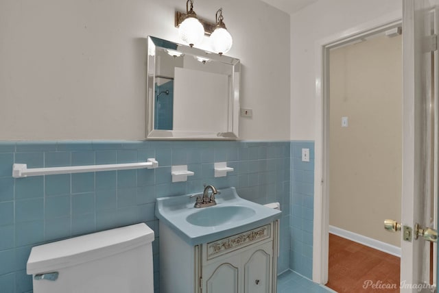 bathroom with wood-type flooring, vanity, toilet, and tile walls