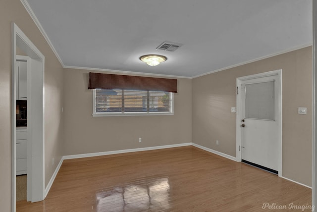 spare room featuring light wood-type flooring and crown molding