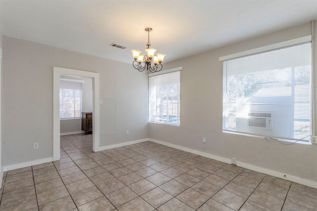 tiled empty room with a chandelier and a textured ceiling