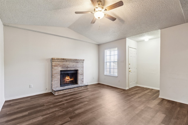 unfurnished living room featuring ceiling fan, vaulted ceiling, dark hardwood / wood-style flooring, and a brick fireplace