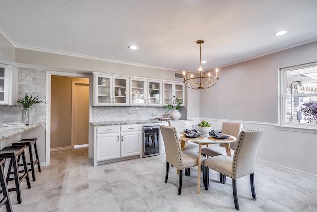 dining room with an inviting chandelier, beverage cooler, and ornamental molding