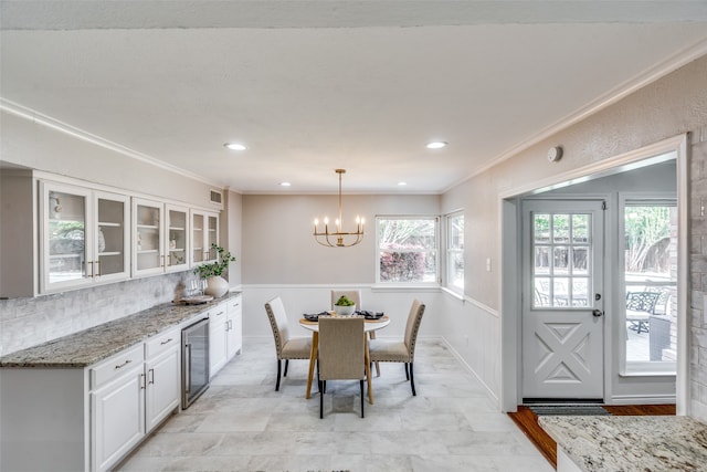 dining room featuring wine cooler, crown molding, and a chandelier