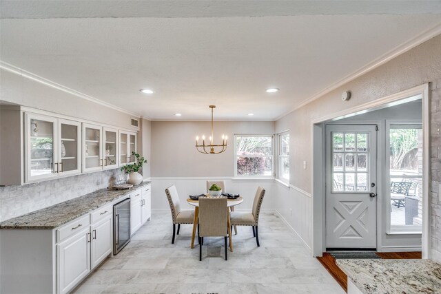 dining room featuring wine cooler, crown molding, and a chandelier