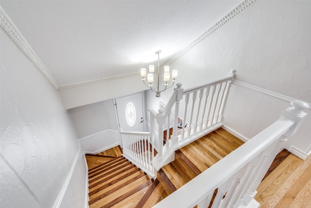 staircase featuring a notable chandelier, crown molding, vaulted ceiling, and hardwood / wood-style flooring