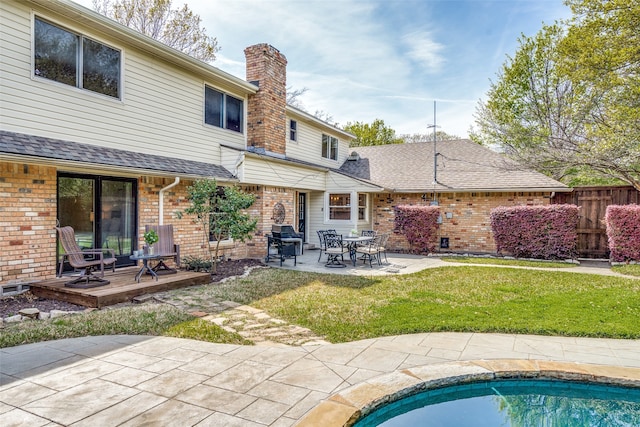 back of property with a yard, a patio area, and a wooden deck