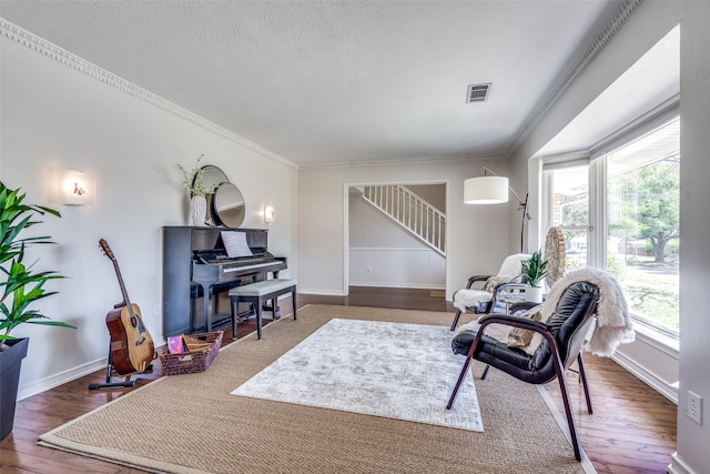 sitting room with a textured ceiling, dark hardwood / wood-style floors, and ornamental molding