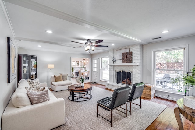 living room with a fireplace, a wealth of natural light, hardwood / wood-style flooring, and crown molding