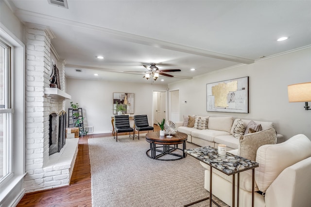 living room featuring a fireplace, wood-type flooring, crown molding, and plenty of natural light