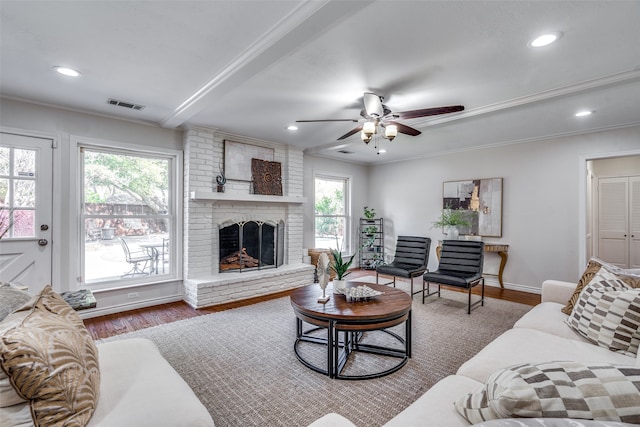 living room with crown molding, ceiling fan, a fireplace, and wood-type flooring