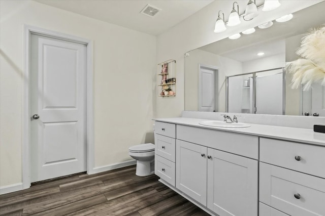 bathroom with hardwood / wood-style floors, vanity, an enclosed shower, and toilet