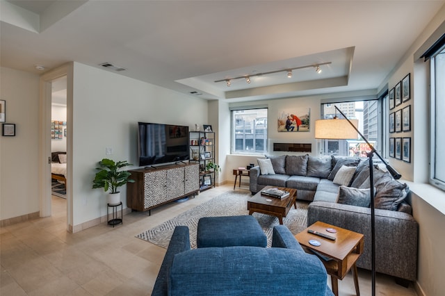 living room with a raised ceiling and rail lighting