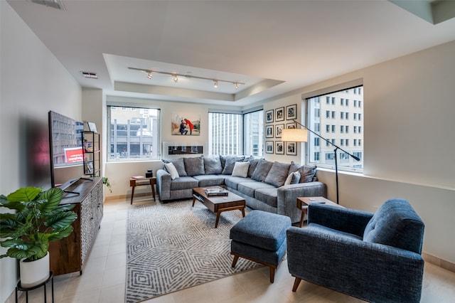 living room with light tile patterned floors, a tray ceiling, and a wealth of natural light