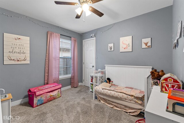 bedroom featuring ceiling fan, light colored carpet, and a nursery area