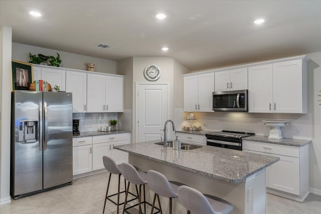 kitchen with white cabinets, stainless steel appliances, a kitchen island with sink, and sink