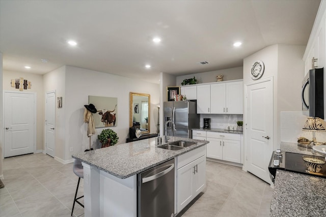 kitchen with white cabinets, decorative backsplash, an island with sink, and stainless steel appliances